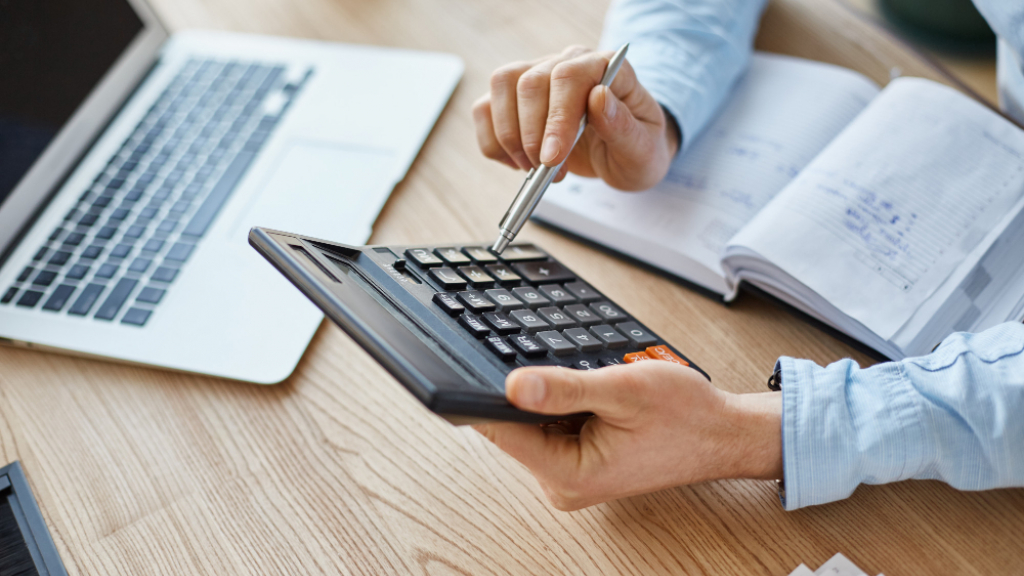 persona fent comptes amb l'ordinador i la calculadora persona fent comptes amb l'ordinador i la calculadora