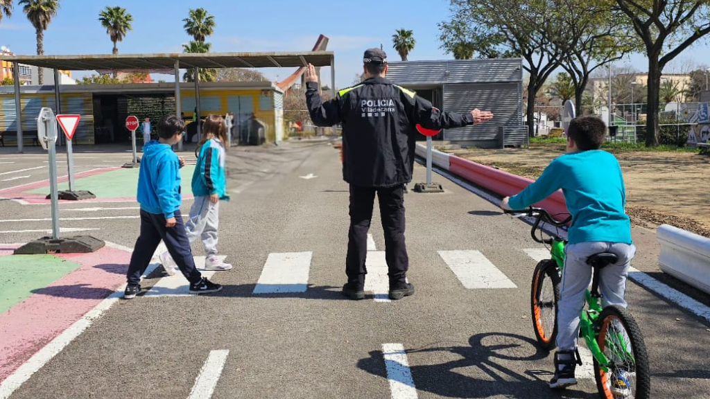 Dos nens i una nena, a les ordres d'un agent al Parc Infantil de Trànsit