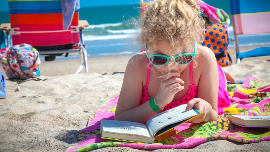 Una nena, llegint a la platja