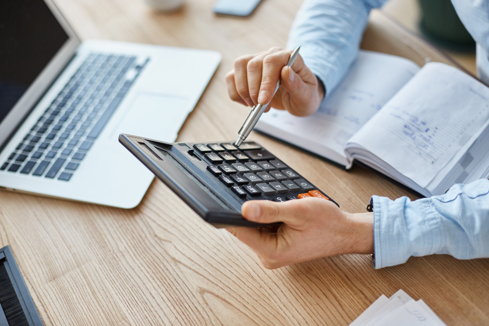 persona fent comptes amb l'ordinador i la calculadora